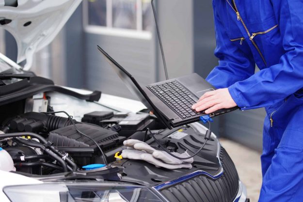 Mechaniker arbeitet mit einem Laptop an einem Auto, Motorsteuerung