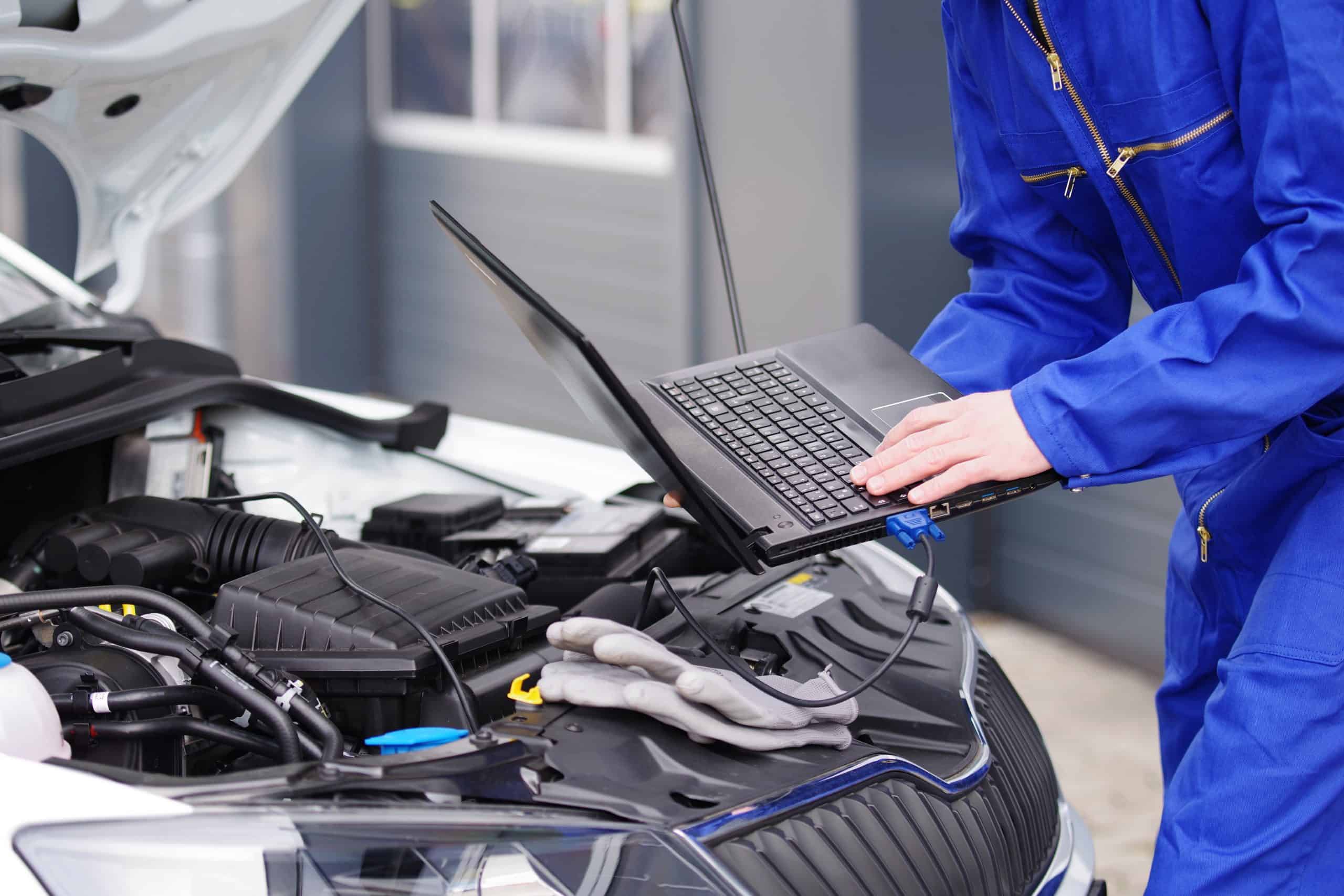 Mechaniker arbeitet mit einem Laptop an einem Auto, Motorsteuerung